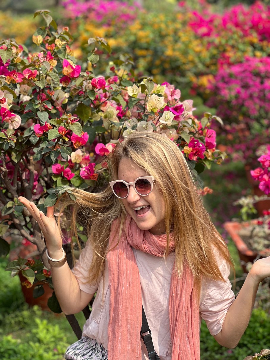 pink lady posing in front of colorful flowers